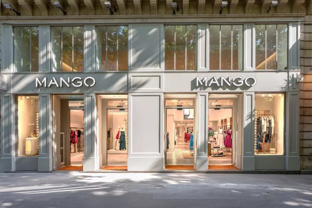 A Mango storefront with two backlit signs above glass doors and window displays