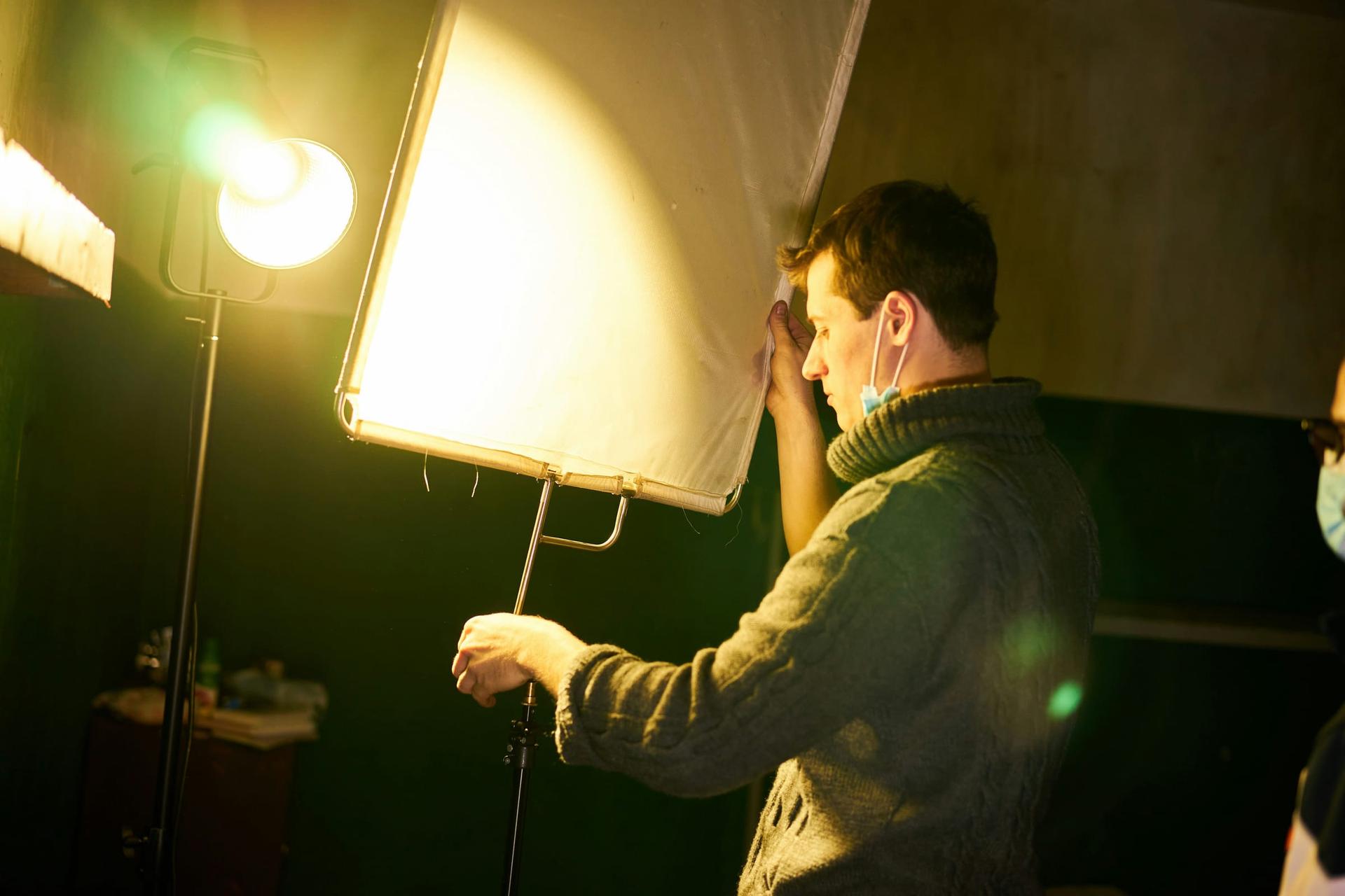 A crew member adjusts lighting equipment backstage before a show