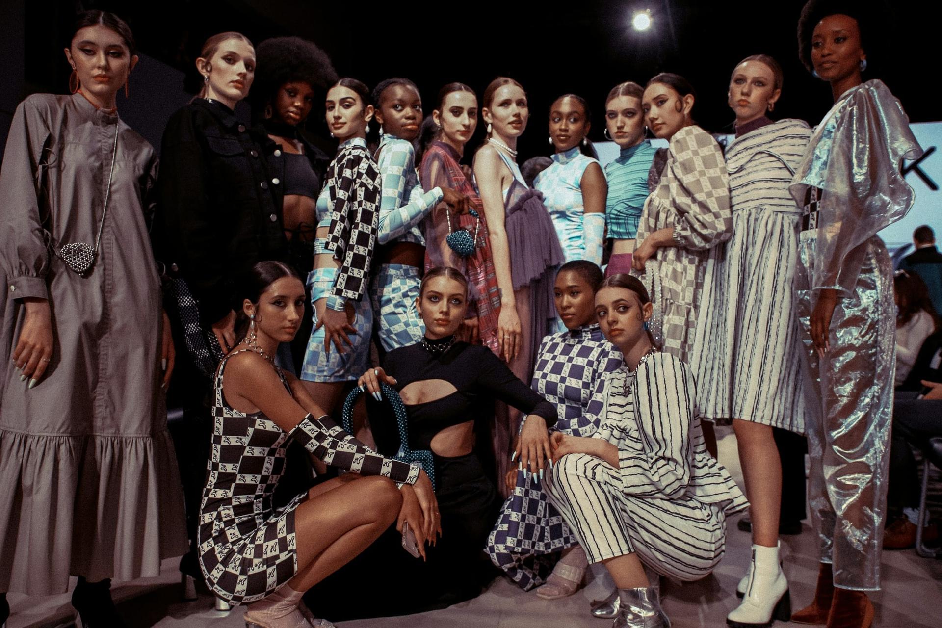 Models in geometric looks gather backstage after a runway show