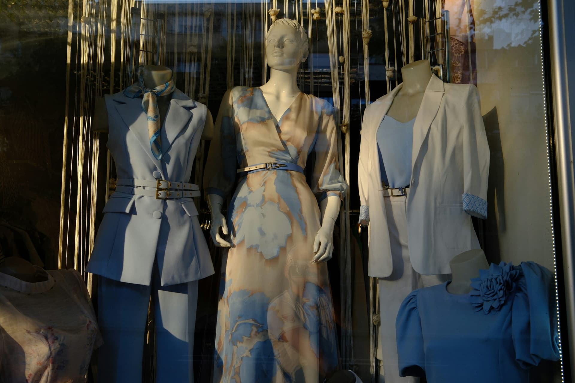 A shop window with mannequins in coordinated pastel blue, white, and floral looks